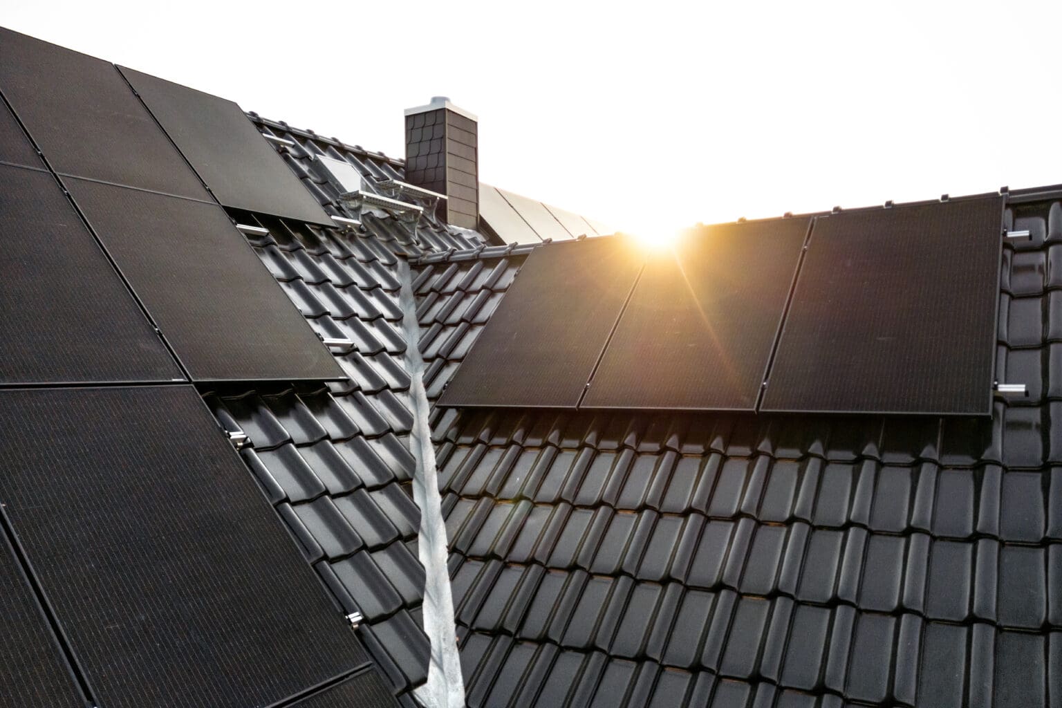 Solar panels on a dark tiled roof captured with a lens flare at